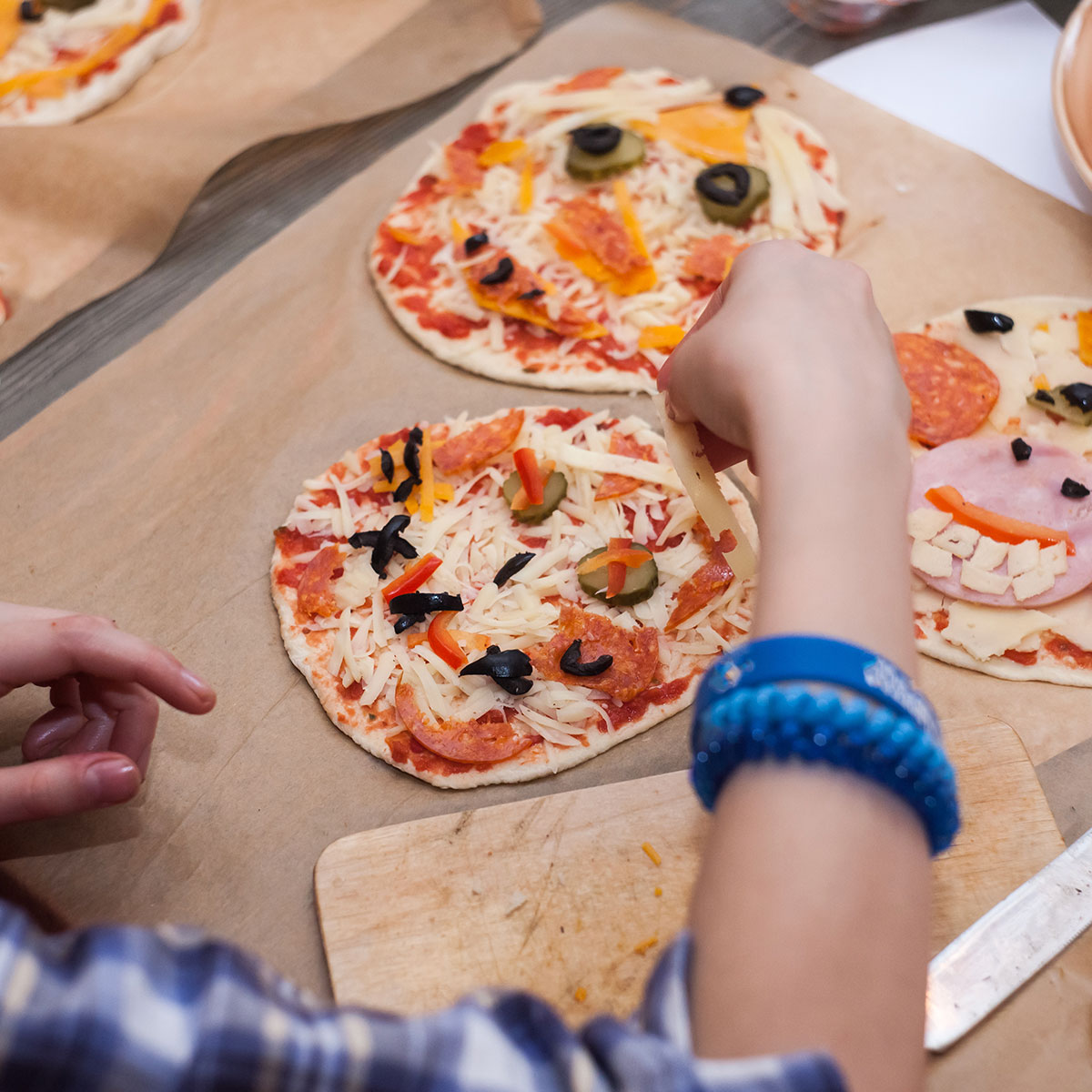 kids hand reaching for a slice of a personal pizza