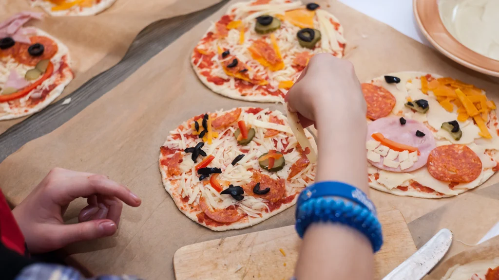 child's hands making pizzas